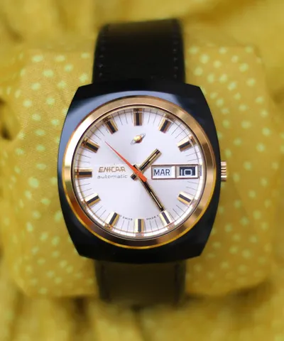 Enicar automatic with a white dial and day-date in a black PVD cushion case with a gold-coloured bezel, on a black strap