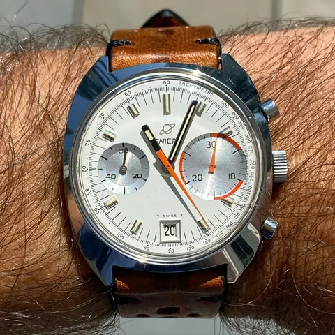 Big Eye with an albino silver dial and orange chronograph hand on a tan rally strap, on the wrist