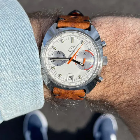 Big Eye with a white dial and orange chronograph hand on a tan strap, on the wrist