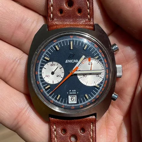 F45 chronograph with a navy dial and orange chronograph hand, held in the hand
