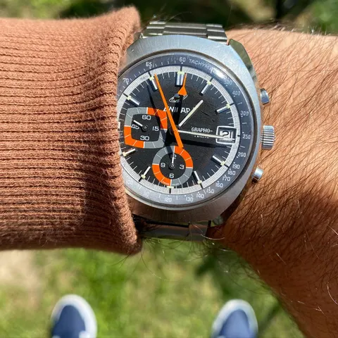 Grapho-Matic with a dark dial and orange hands on a steel bracelet, on the wrist