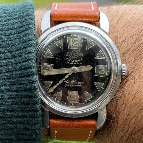 Enicar Healthways 100 Fathoms with a worn black dial, triangle markers and Arabic 12, 3, 6 and 9 on a tan strap, on the wrist