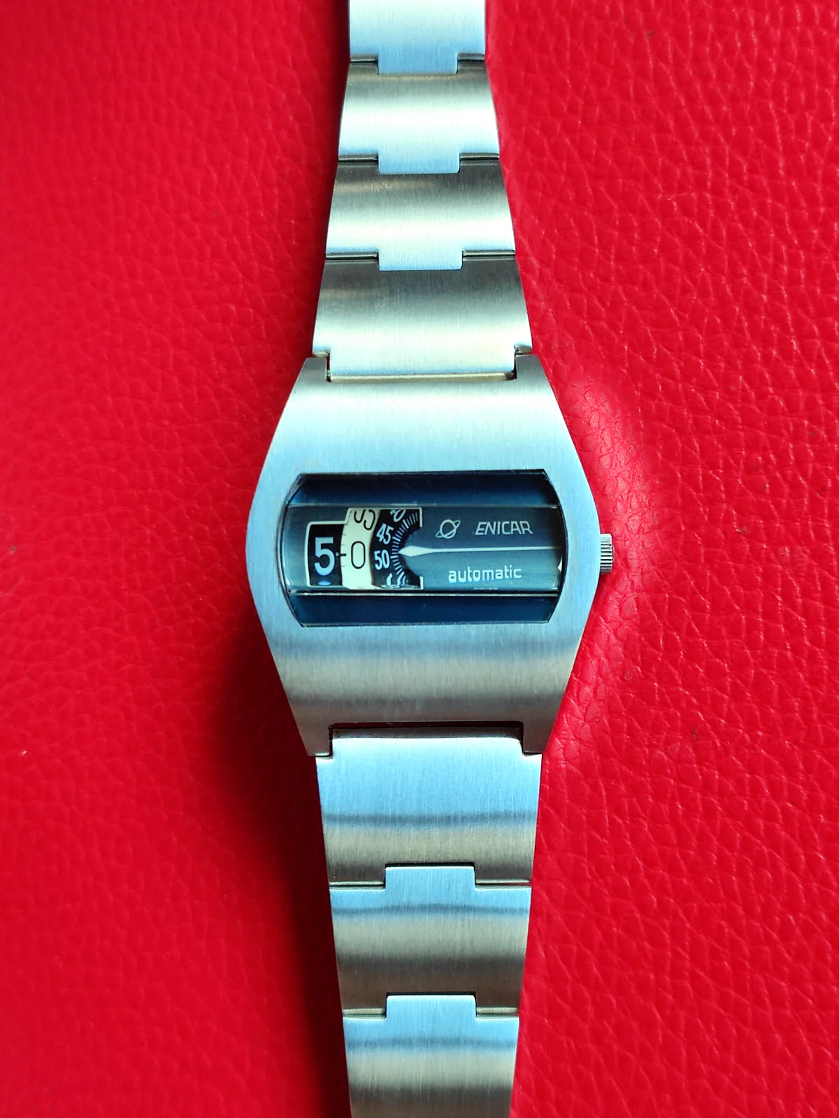 Enicar Jump Hour with a blue dial in a brushed steel tonneau case on its integrated bracelet
