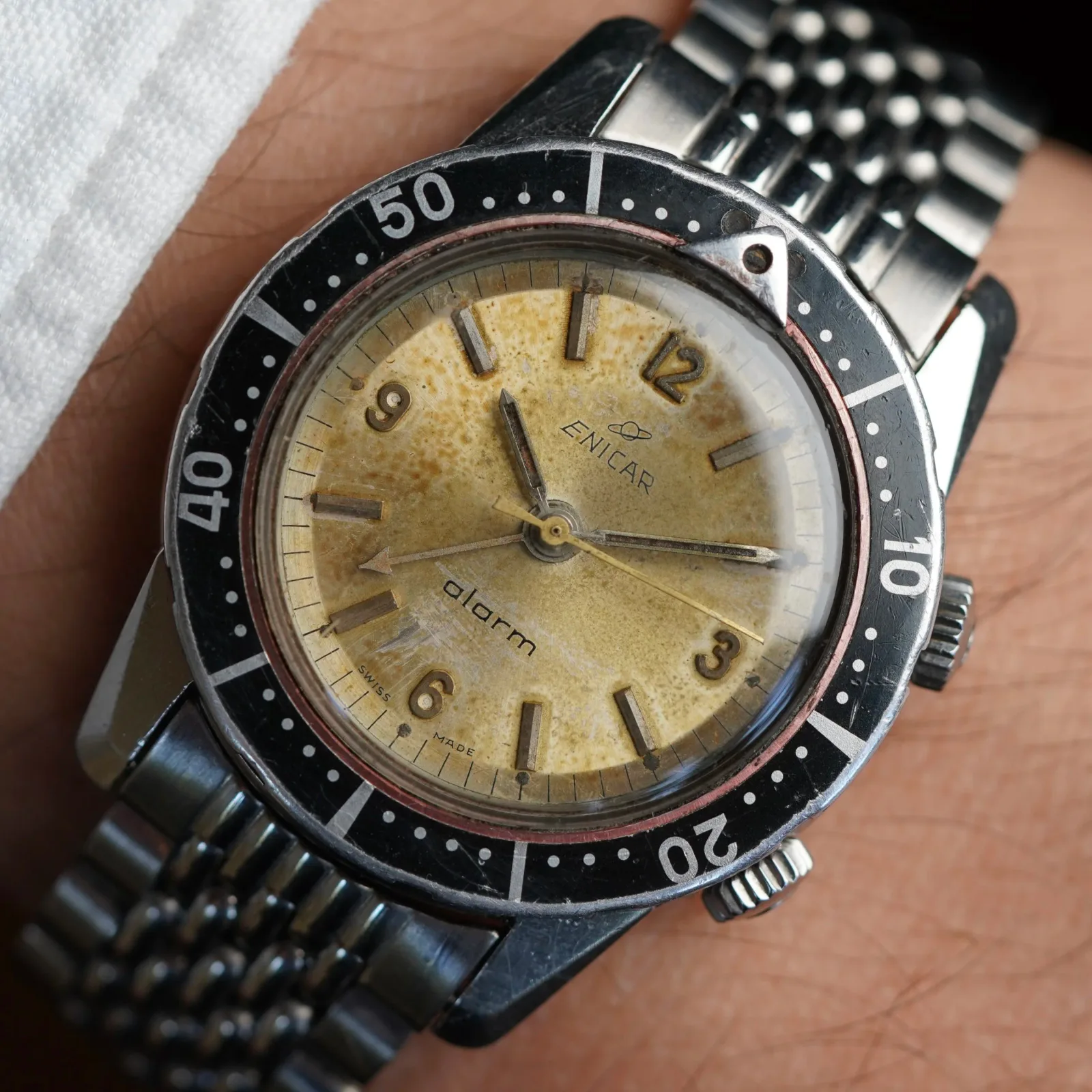 Enicar dive alarm with an aged cream dial, black rotating bezel and steel bracelet, on the wrist