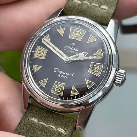 Seapearl 600 with a tropical brown dial, triangle and Arabic markers on an olive suede strap, held in the hand