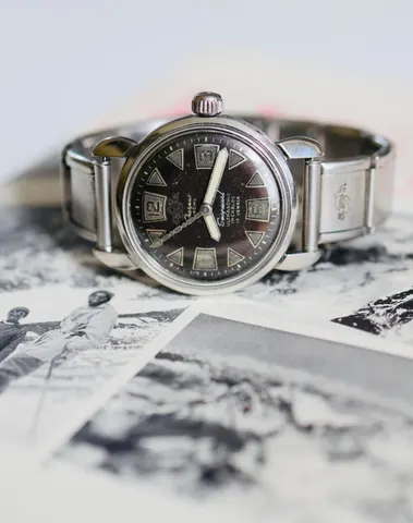 Seapearl from 1956 with a black dial on an expanding bracelet, lying on old photographs
