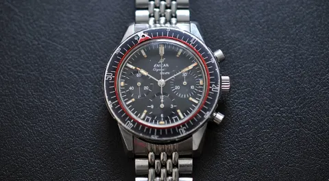 Aqua Graph with an all-black dial, black 60-minute bezel and red pointer ring, on a beads-of-rice bracelet
