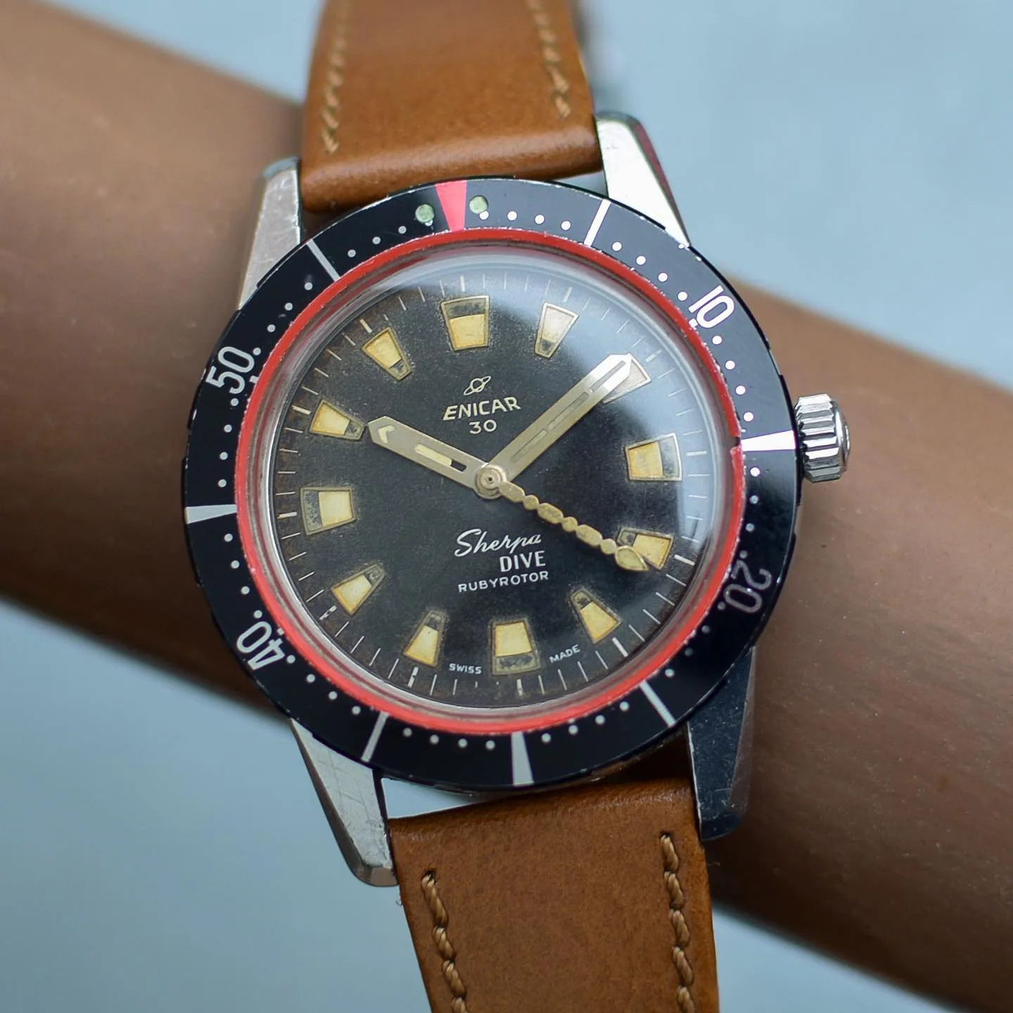 Sherpa Dive with a black dial, red pointer ring and black outer bezel on a tan leather strap