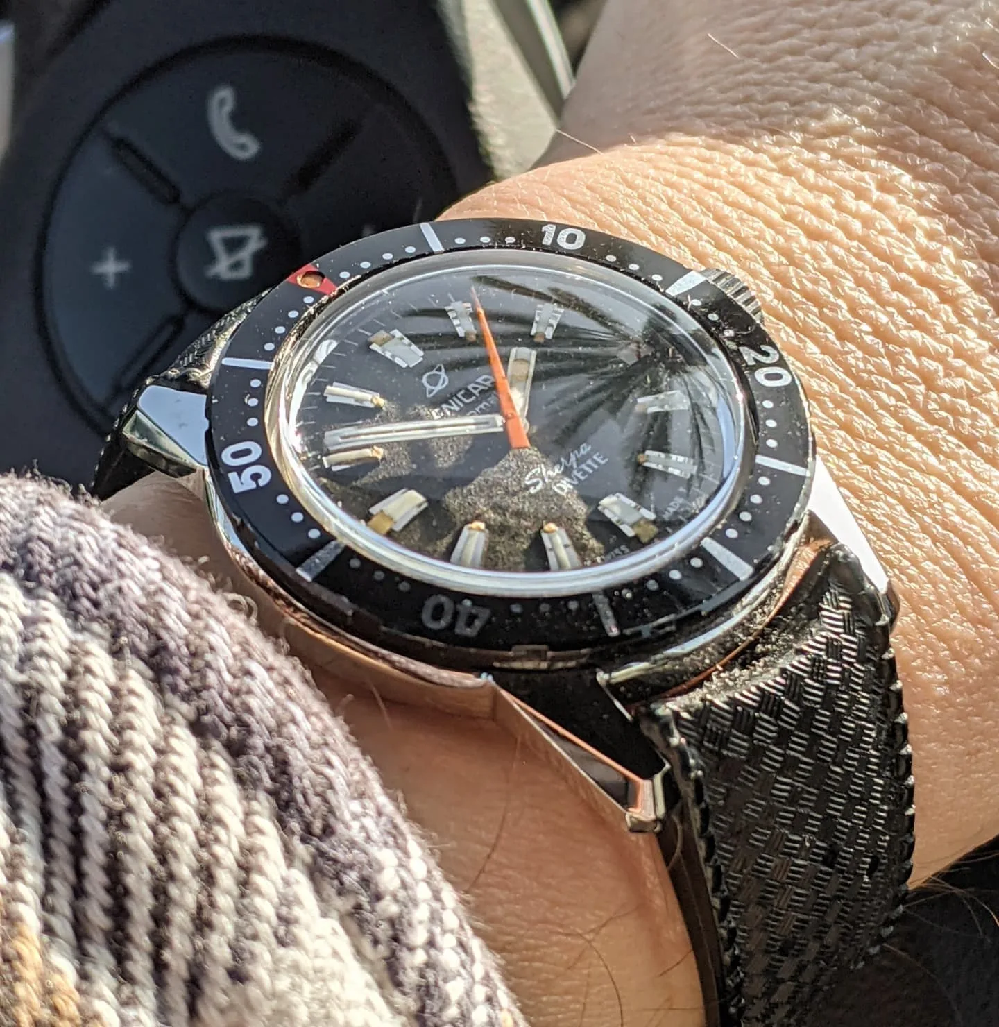 Sherpa Divette with a black dial, orange seconds hand and black outer bezel on a black strap