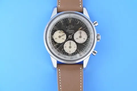 Sherpa Graph MkI with a black dial and cream registers on a brown strap, against a blue background