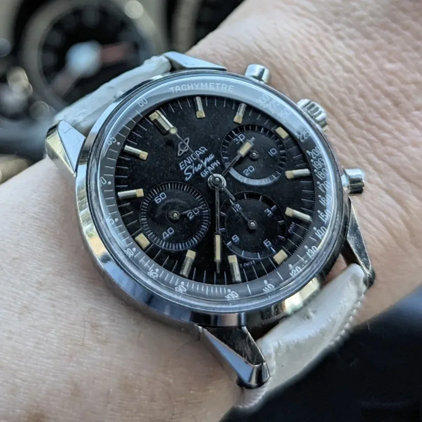 Sherpa Graph with a black dial and black subdials on a white strap, on the wrist