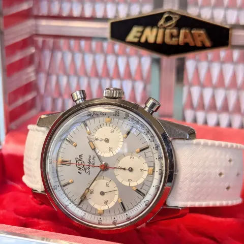 Sherpa Graph with a silver dial and cream subdials on a white strap, in front of a red-lined Enicar display box
