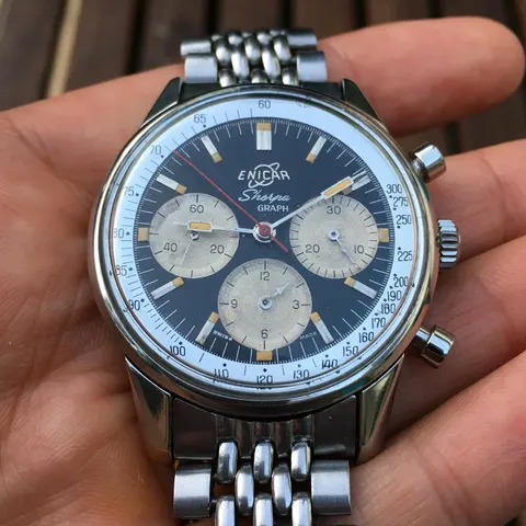 Sherpa Graph with a black dial, silver registers and white tachymetre ring on a steel bracelet, held in the hand