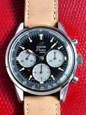Sherpa Graph MkIII with a black dial and grey registers on a tan strap, against a red background