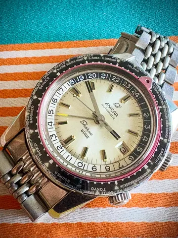 Sherpa Guide automatic with a silver dial and world-city outer bezel on a steel bracelet, seen at an angle