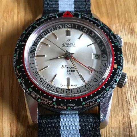 Sherpa Guide with a silver dial marked 33 and world-city bezel on a grey striped strap