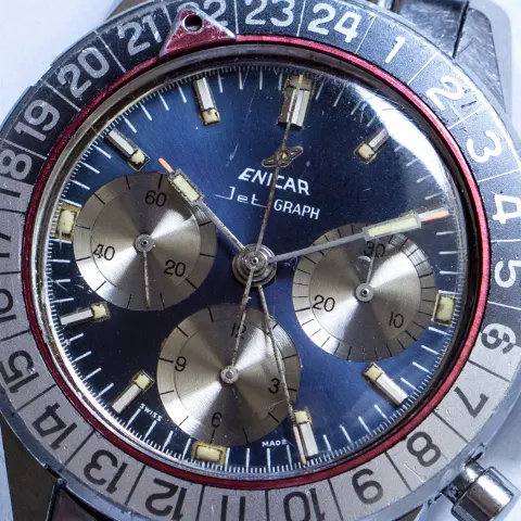 Close-up of a blue Jet Graph dial with silver registers inside a red ring and 24-hour bezel