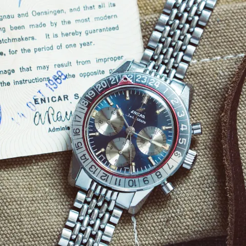 Blue-dial Jet Graph on a beads-of-rice bracelet lying on its Enicar guarantee card