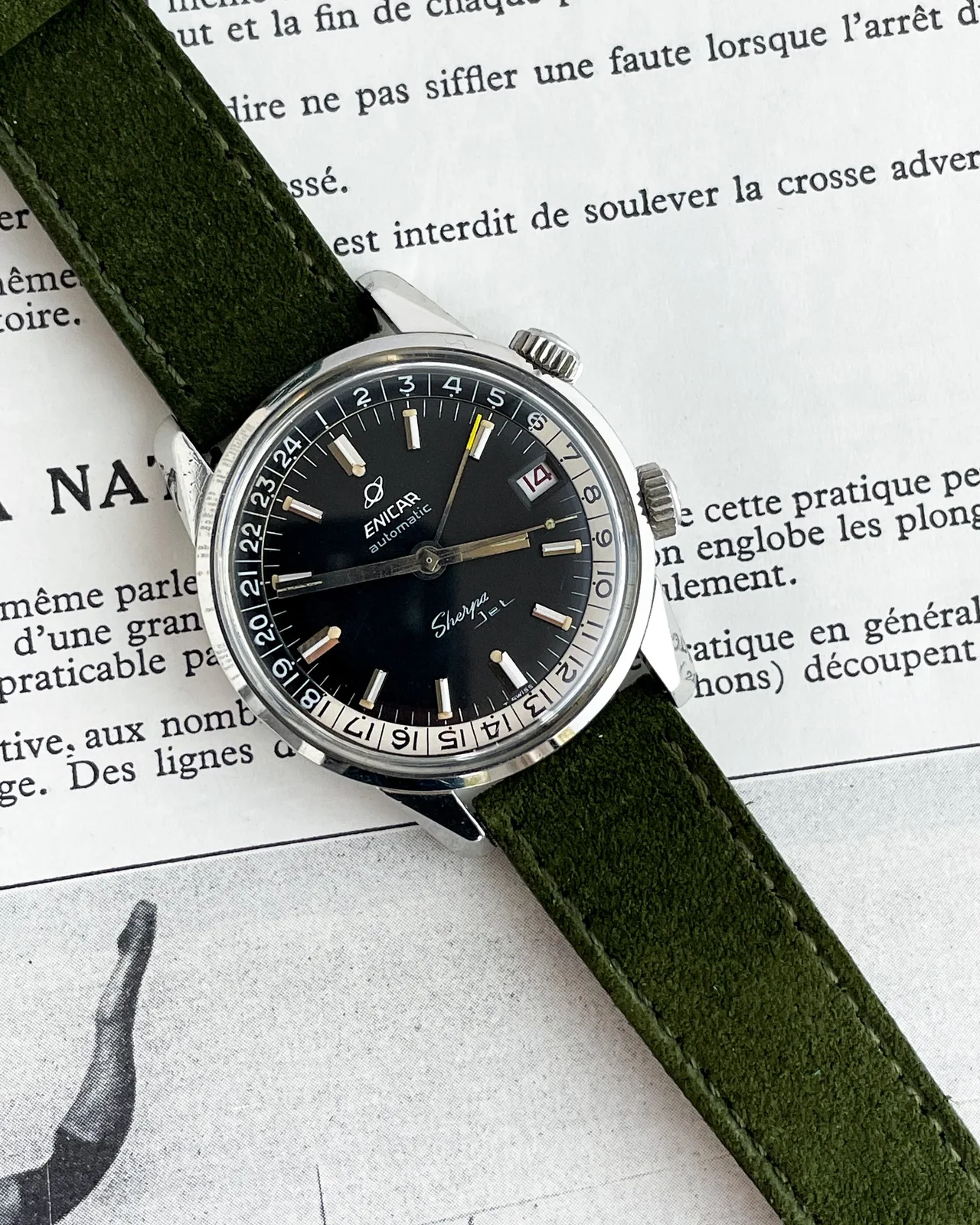 Sherpa Jet with a black dial and white and black 24-hour bezel on a green suede strap, on a printed page
