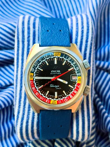 Sherpa Jet automatic in a cushion case with a black dial, red and blue inner bezel with yellow markers and date at 3, on a blue strap