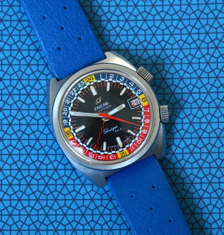 Sherpa Jet automatic in a cushion case with a black dial and red, blue and yellow inner bezel, on a blue strap over a blue patterned cloth
