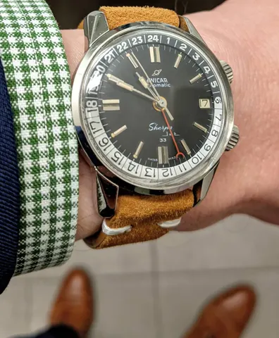Sherpa Jet 33 with a black dial and black and silver 24-hour bezel on a tan suede strap