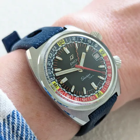 Sherpa Jet in a cushion case with a black dial and red, blue and yellow inner bezel on a blue strap