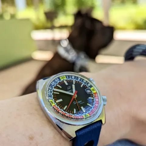 Sherpa Jet in a cushion case with a black dial and red and blue inner bezel with yellow markers, on a blue strap