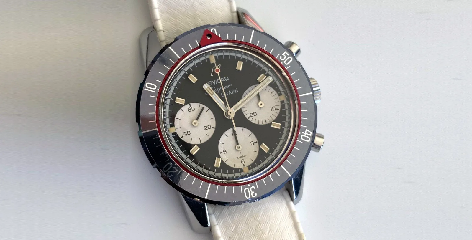 Super Graph MkIII with a black dial, silver registers, red pointer ring and grey 60-minute bezel, on a white strap