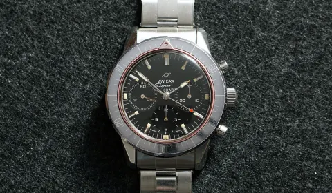 Super Graph with an all-black dial, grey countdown bezel and red ring, on a steel bracelet